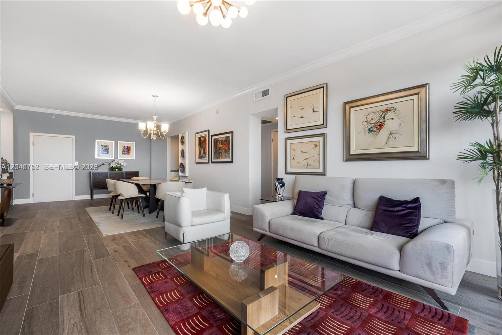 A living and dining area features wood-look tile floors, a glass coffee table, and artwork — 90 Edgewater Dr, Coral Gables FL 33133, CORAL GABLES, FL