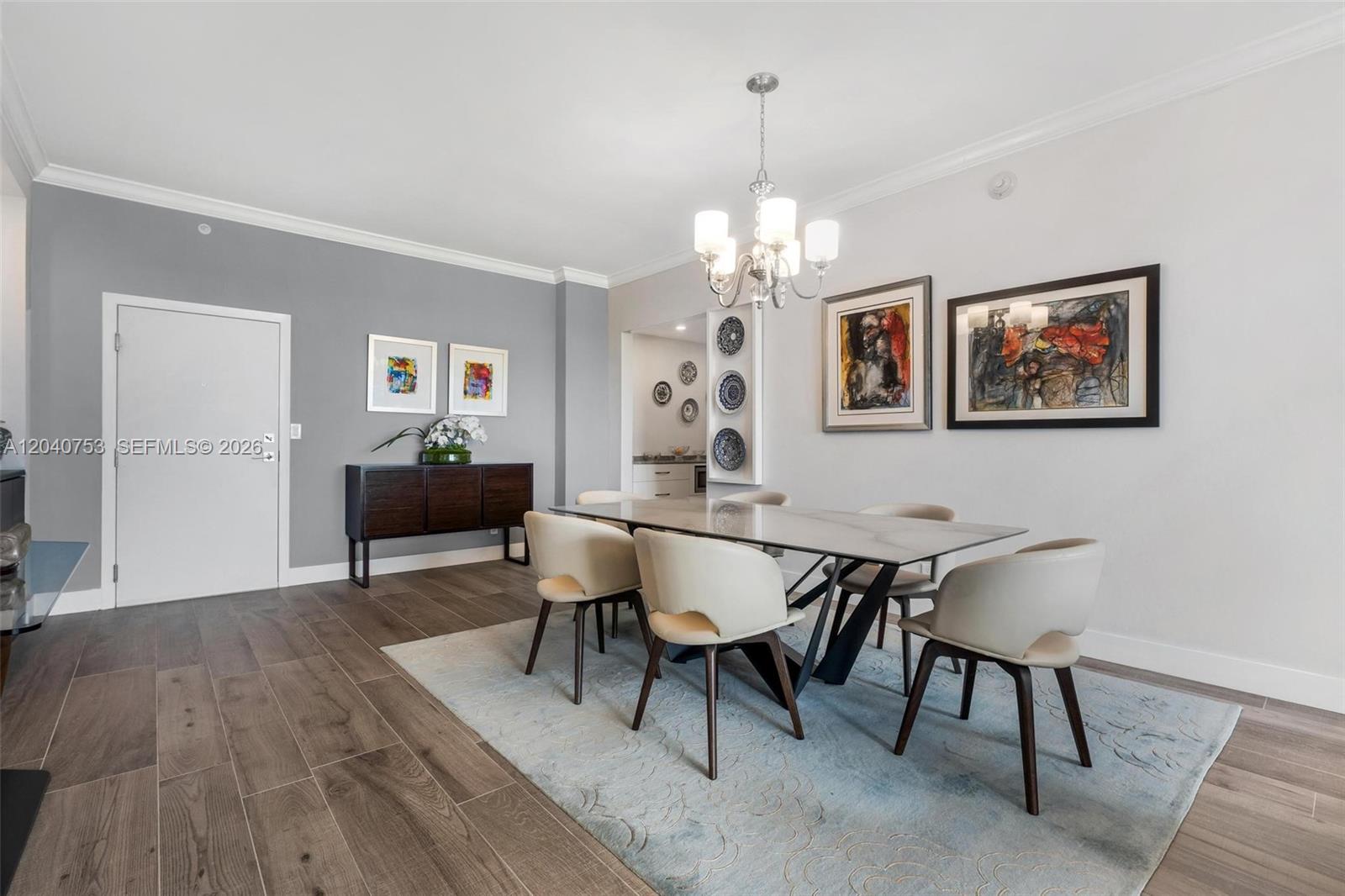 A dining room features a glass table, cream chairs, a chandelier, and gray accent walls — 90 Edgewater Dr, Coral Gables FL 33133, CORAL GABLES, FL