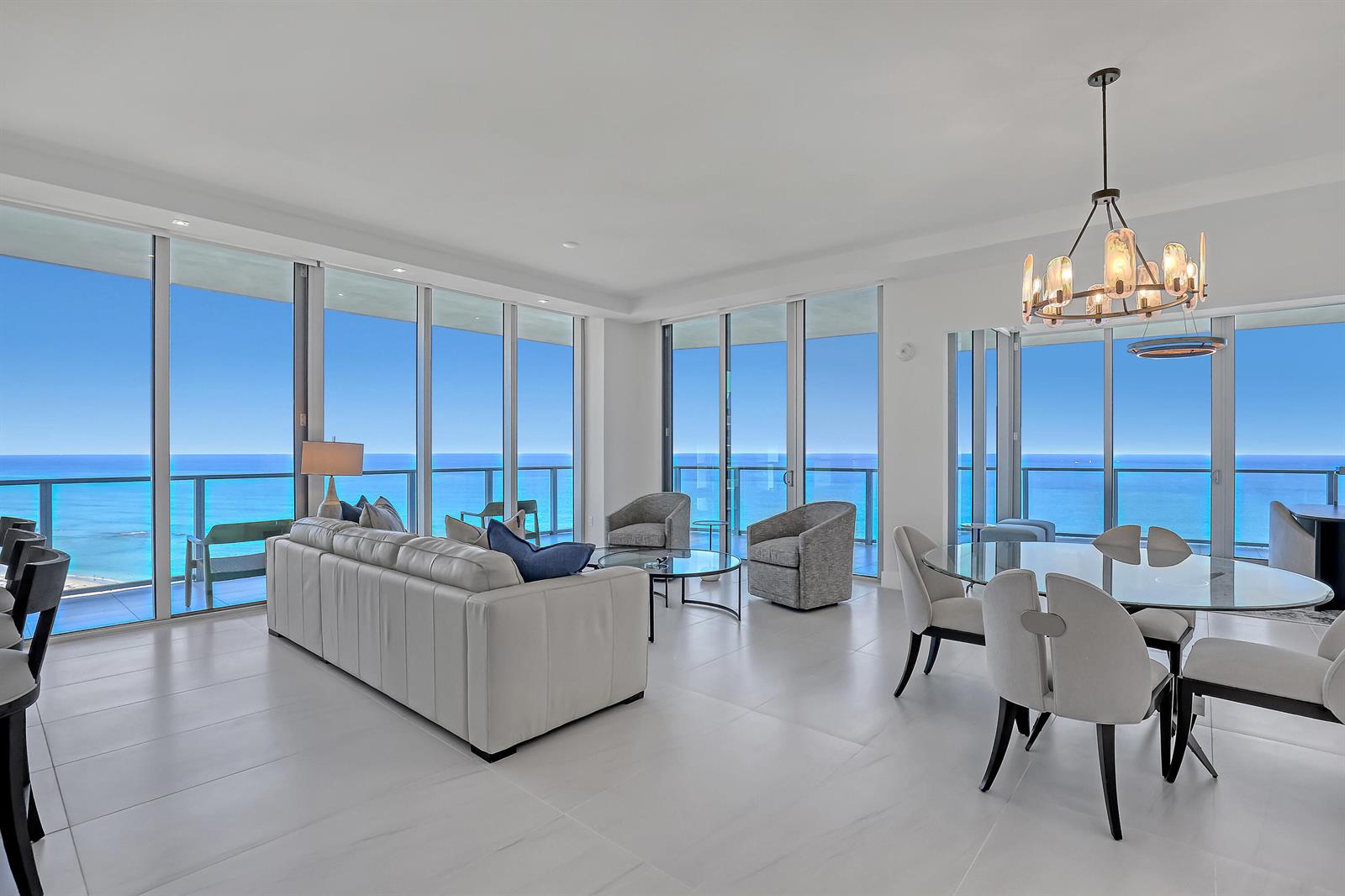A bright living and dining area features floor-to-ceiling windows with expansive ocean views — 3100 N Ocean Drive # 1703, Riviera Beach FL 33404, RIVIERA BEACH, FL