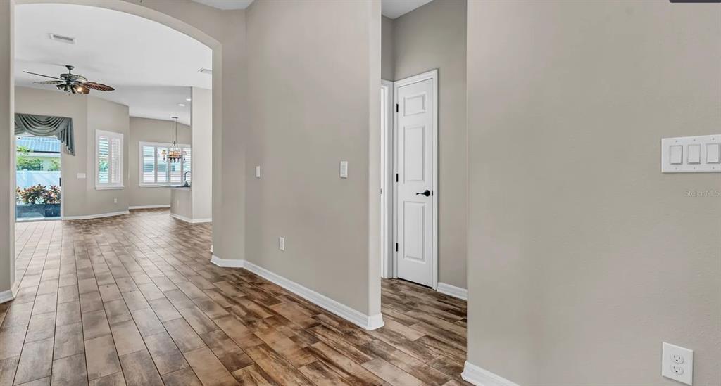 A hallway with wood-look tile flooring leads to an open living area with a ceiling fan — 7328 BLUE BEECH DRIVE, RIVERVIEW, FL