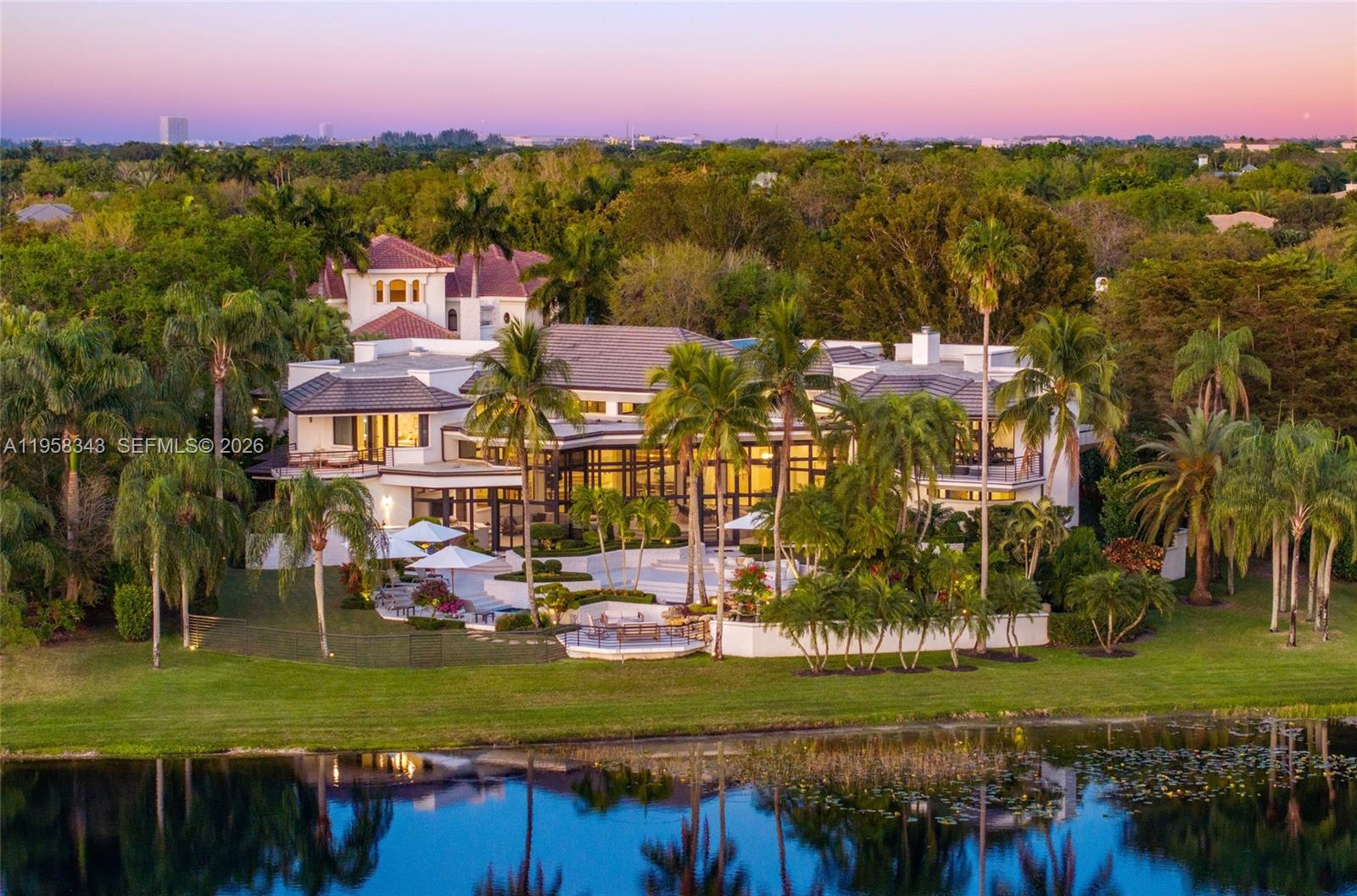 An aerial view shows a large multi-story house with a pool and patio by a lake — 2965 Surrey Ln, Weston FL 33331, WESTON, FL