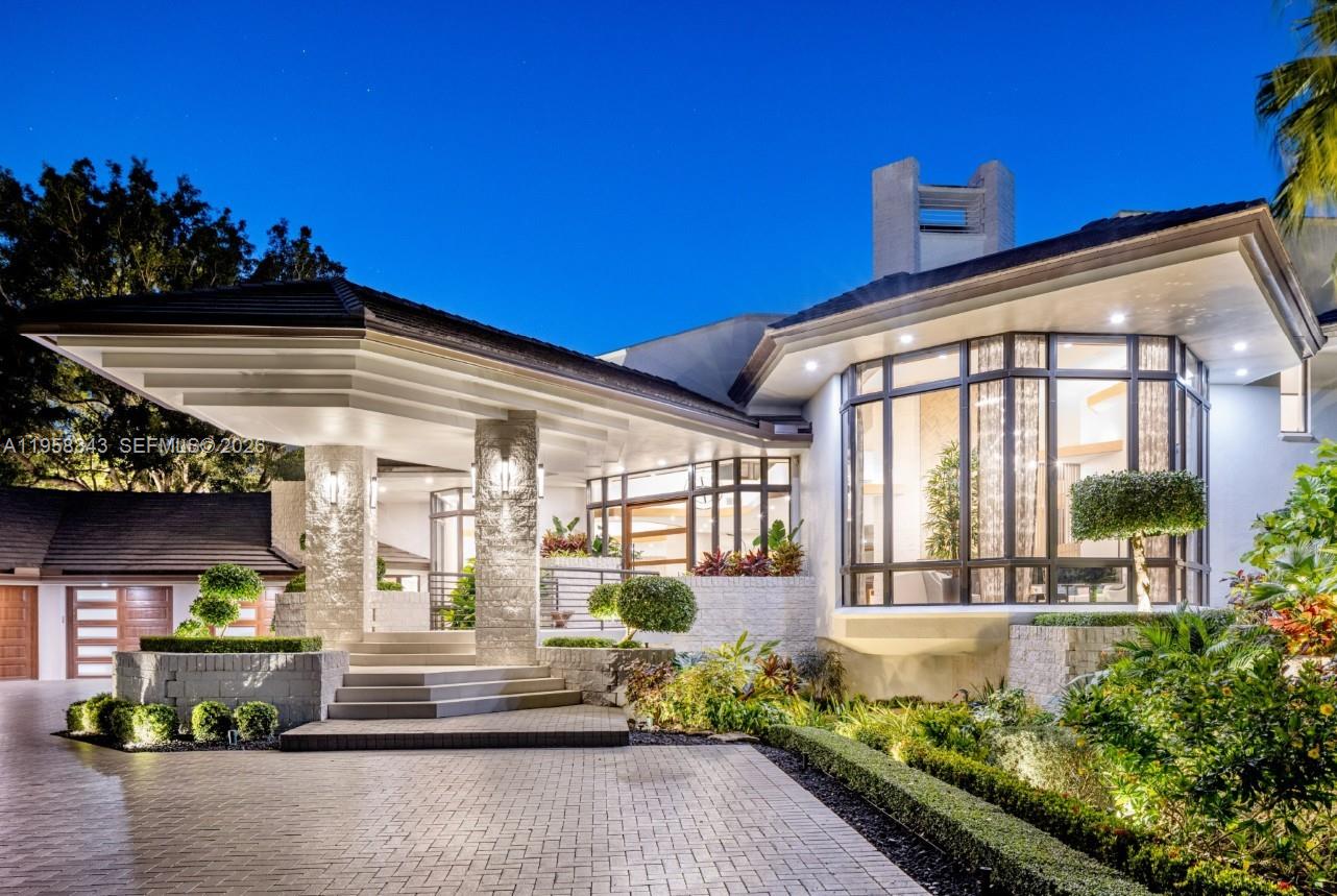 A modern house exterior features a stone-pillared entryway, large glass windows, and a paved driveway — 2965 Surrey Ln, Weston FL 33331, WESTON, FL