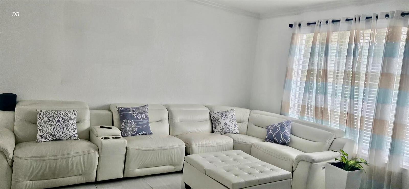 A white sectional sofa with a matching ottoman sits in a living room with curtains — 400 SW 15th Drive, Boca Raton FL 33432, BOCA RATON, FL