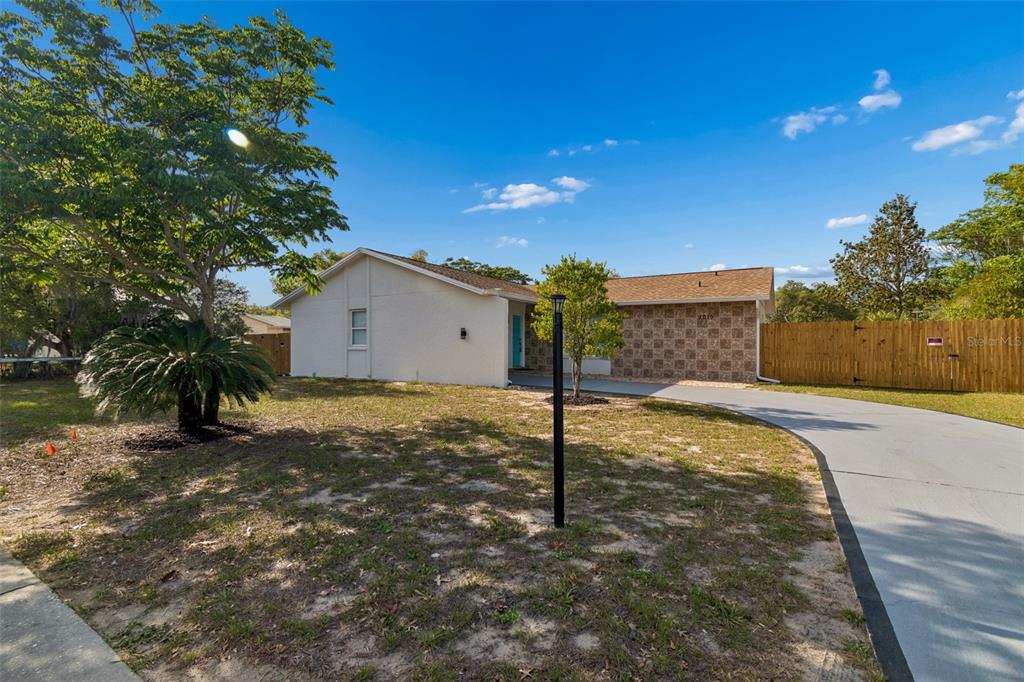 A single-story house with a white exterior, stone facade, and a curved concrete driveway — 9015 FOREST OAKS BOULEVARD, SPRING HILL, FL