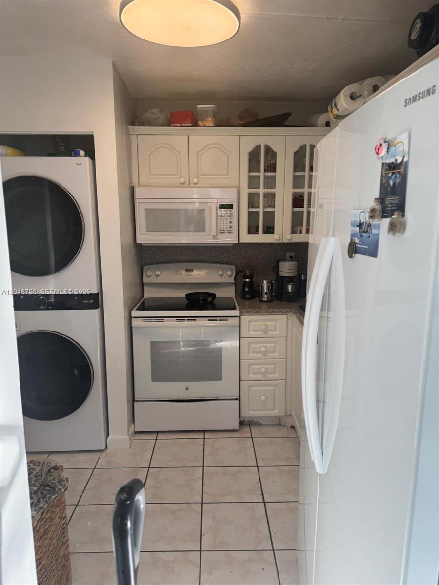 A small kitchen features white appliances, cabinetry, and a stacked washer and dryer unit — 6901 SW 129th Ave # 4, Miami FL 33183, MIAMI, FL