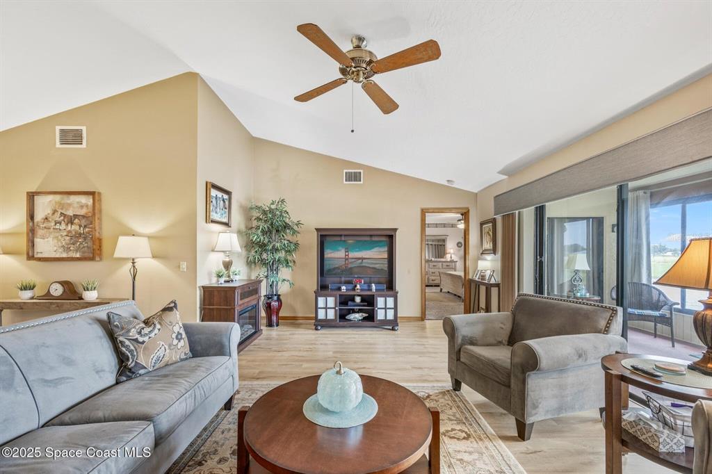 A living room features a vaulted ceiling, a ceiling fan, and a sliding glass door — 1311 ISLAND GREEN DRIVE NE UNIT B2-12, PALM BAY, FL