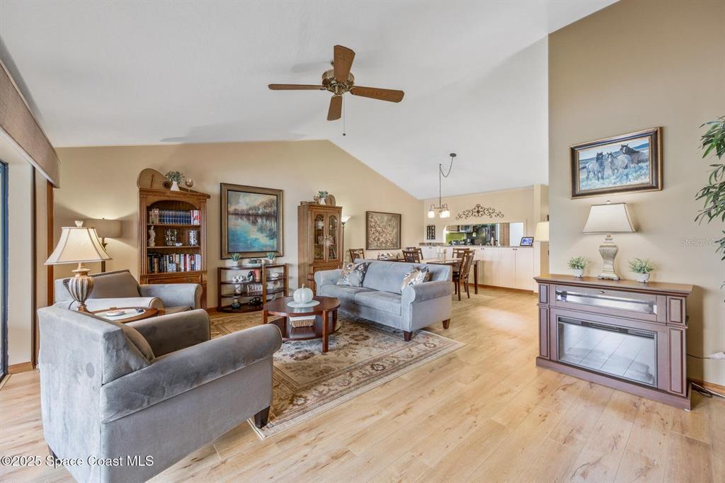 A living room with light wood flooring, vaulted ceilings, a ceiling fan, and furniture — 1311 ISLAND GREEN DRIVE NE UNIT B2-12, PALM BAY, FL
