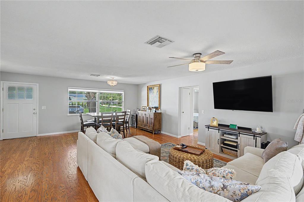 A living room with hardwood floors, a white sectional sofa, and a dining area — 1223 S SAN REMO AVENUE, CLEARWATER, FL