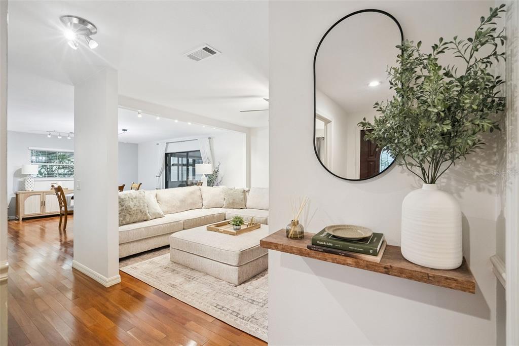 A wooden floating shelf with decor sits in a hallway overlooking a living room area — 636 SWALLOW DRIVE, CASSELBERRY, FL