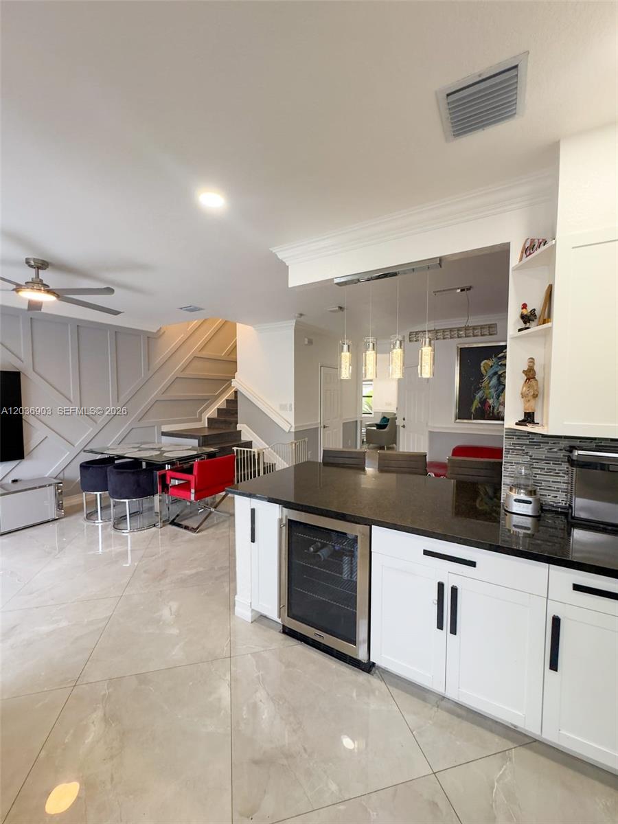 A kitchen with a black granite island and wine cooler overlooks a dining area — 4715 Caspian Way, Davie FL 33314, DAVIE, FL
