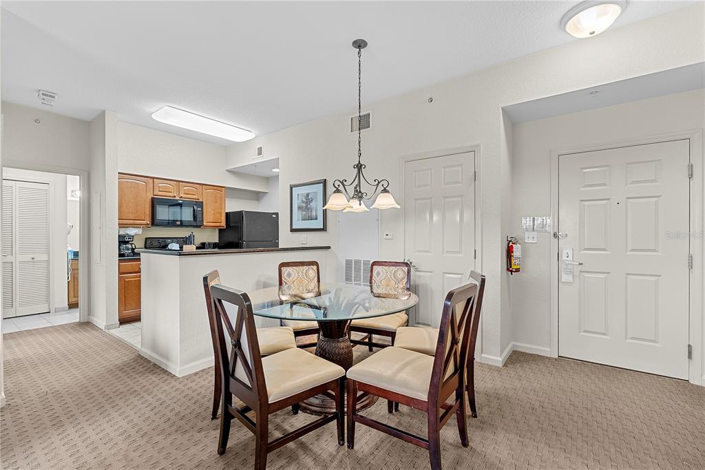 A dining area with a glass table and four chairs sits adjacent to a kitchen — 8112 POINCIANA BOULEVARD UNIT 1306, ORLANDO, FL
