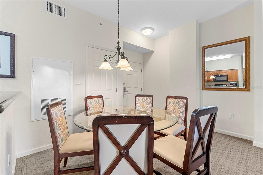 A dining area features a glass-topped table, four patterned chairs, and a hanging light fixture — 8112 POINCIANA BOULEVARD UNIT 1306, ORLANDO, FL