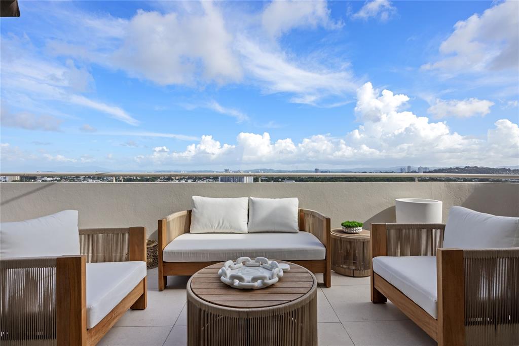 A balcony features a wooden sofa and two armchairs arranged around a round coffee table — 225 ROAD NO 2, VILLA CAPARRA PLAZA UNIT PH-3, GUAYNABO, PR