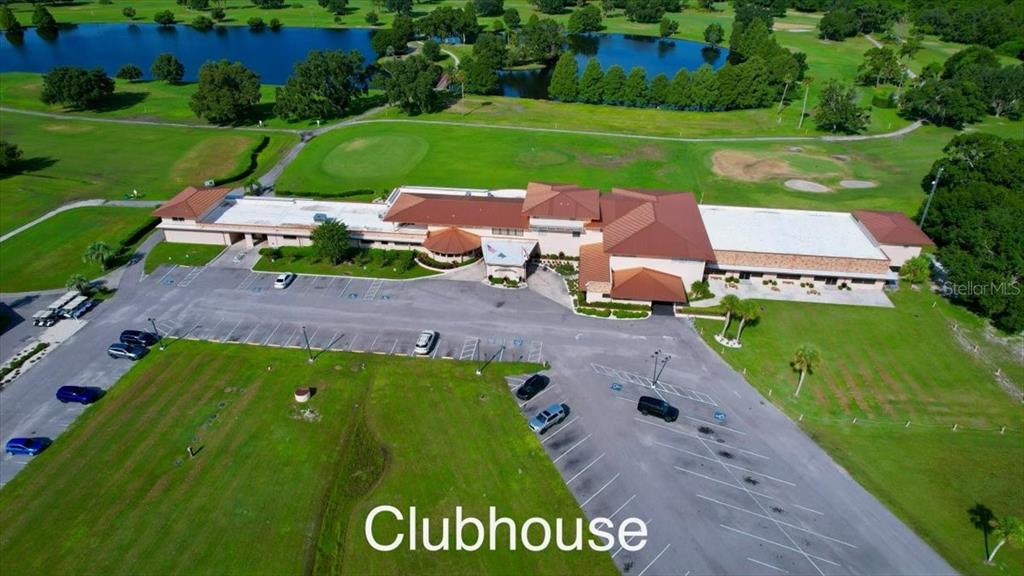 An aerial view shows a large clubhouse building with a parking lot and surrounding golf course — 623 JAPONICA AVENUE, INDIAN LAKE ESTATES, FL