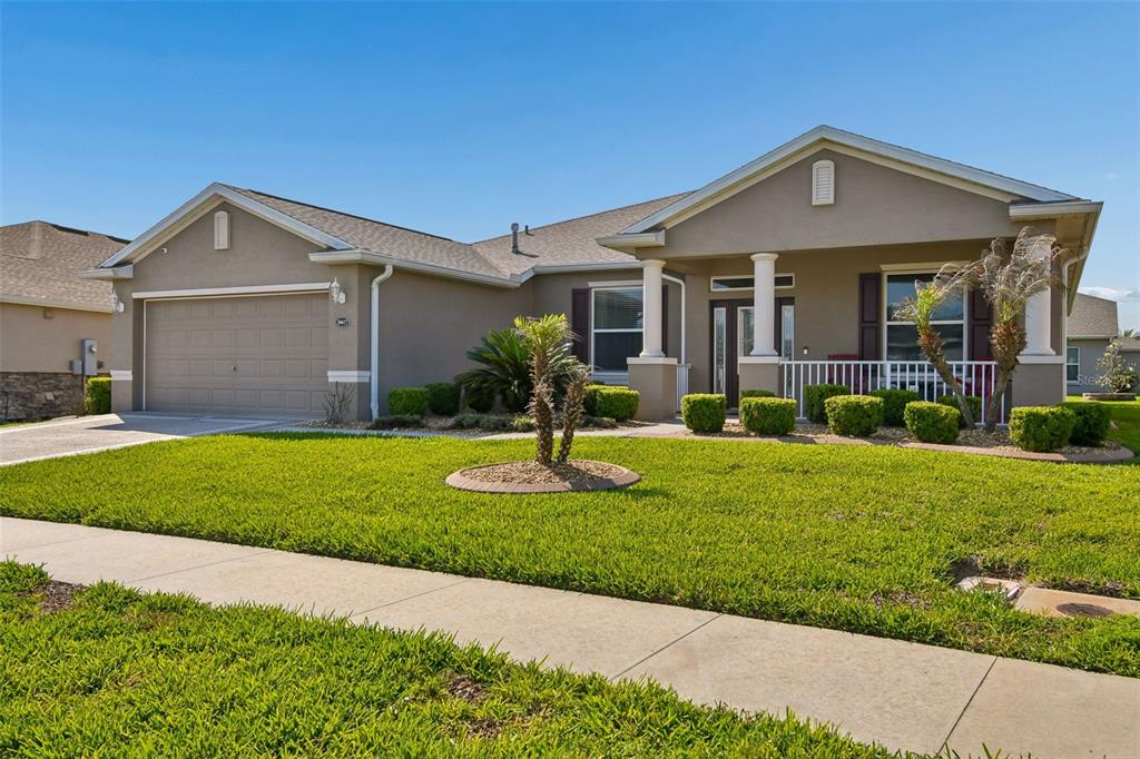 A single-story suburban house with a two-car garage, front porch, and manicured lawn — 26617 OTTER CREEK LANE, LEESBURG, FL
