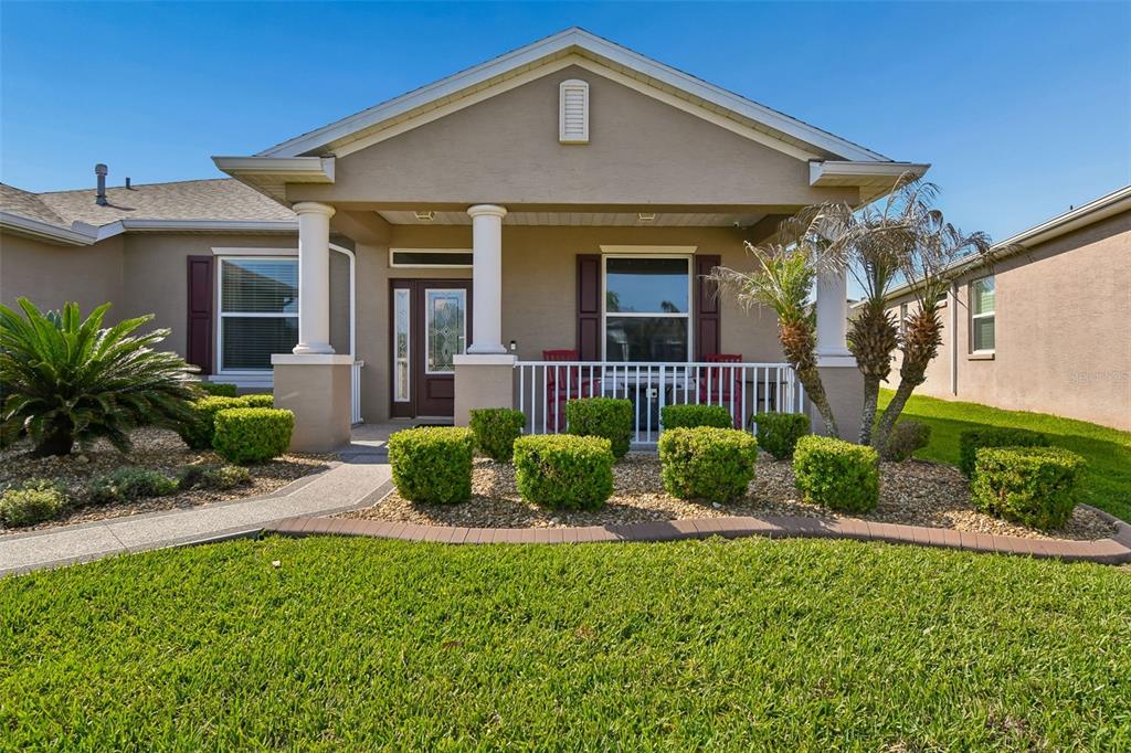 A single-story house exterior features a covered front porch, white columns, and manicured landscaping — 26617 OTTER CREEK LANE, LEESBURG, FL