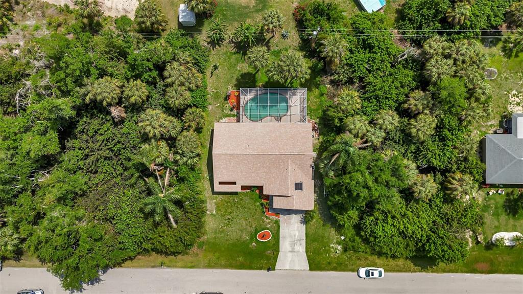 An aerial view shows a house with a screened-in pool surrounded by dense trees — 23177 RYE AVENUE, PUNTA GORDA, FL