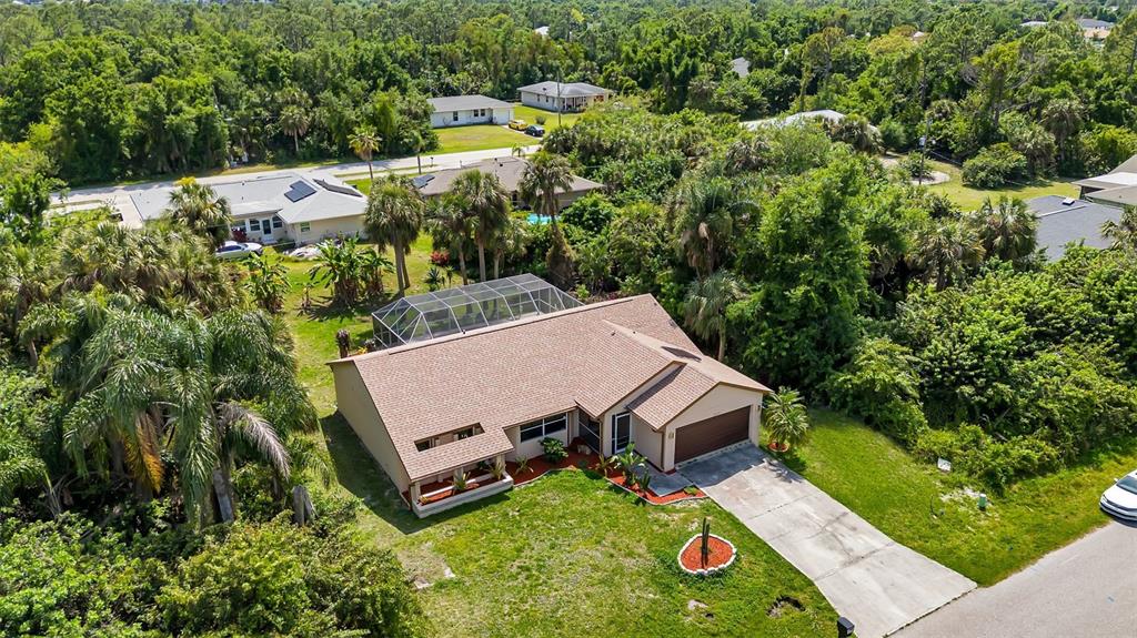 An aerial view shows a single-story house with a screened pool enclosure and driveway — 23177 RYE AVENUE, PUNTA GORDA, FL