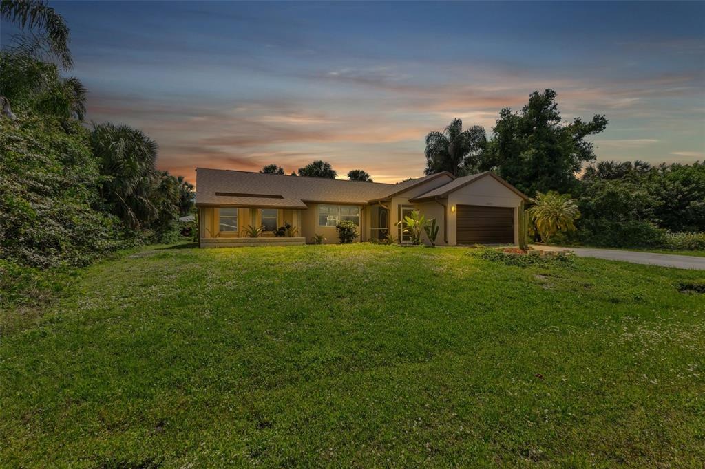 A single-story house with a brown garage and a large front lawn at sunset — 23177 RYE AVENUE, PUNTA GORDA, FL
