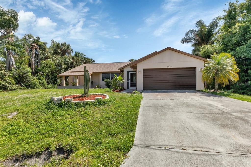 A single-story house with a brown garage, a concrete driveway, and a cactus in front — 23177 RYE AVENUE, PUNTA GORDA, FL