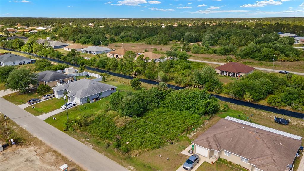 An aerial view shows a residential street with several houses, a vacant lot, and a canal — 1518 HAVILAND AVE S, LEHIGH ACRES, FL