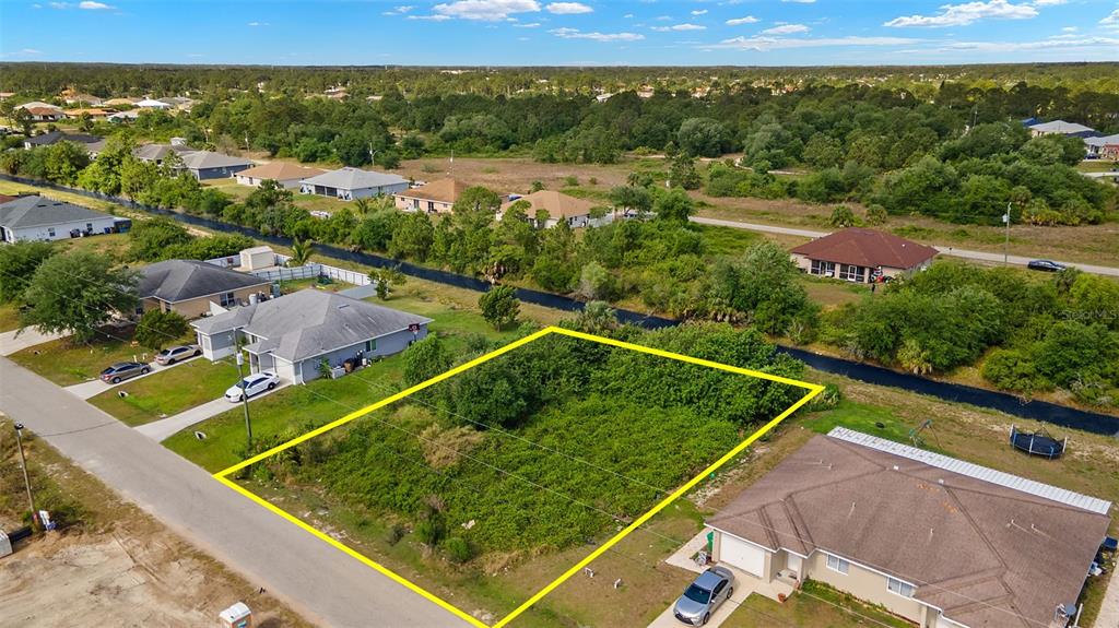 An aerial view shows a vacant, rectangular lot outlined in yellow between two suburban houses — 1518 HAVILAND AVE S, LEHIGH ACRES, FL