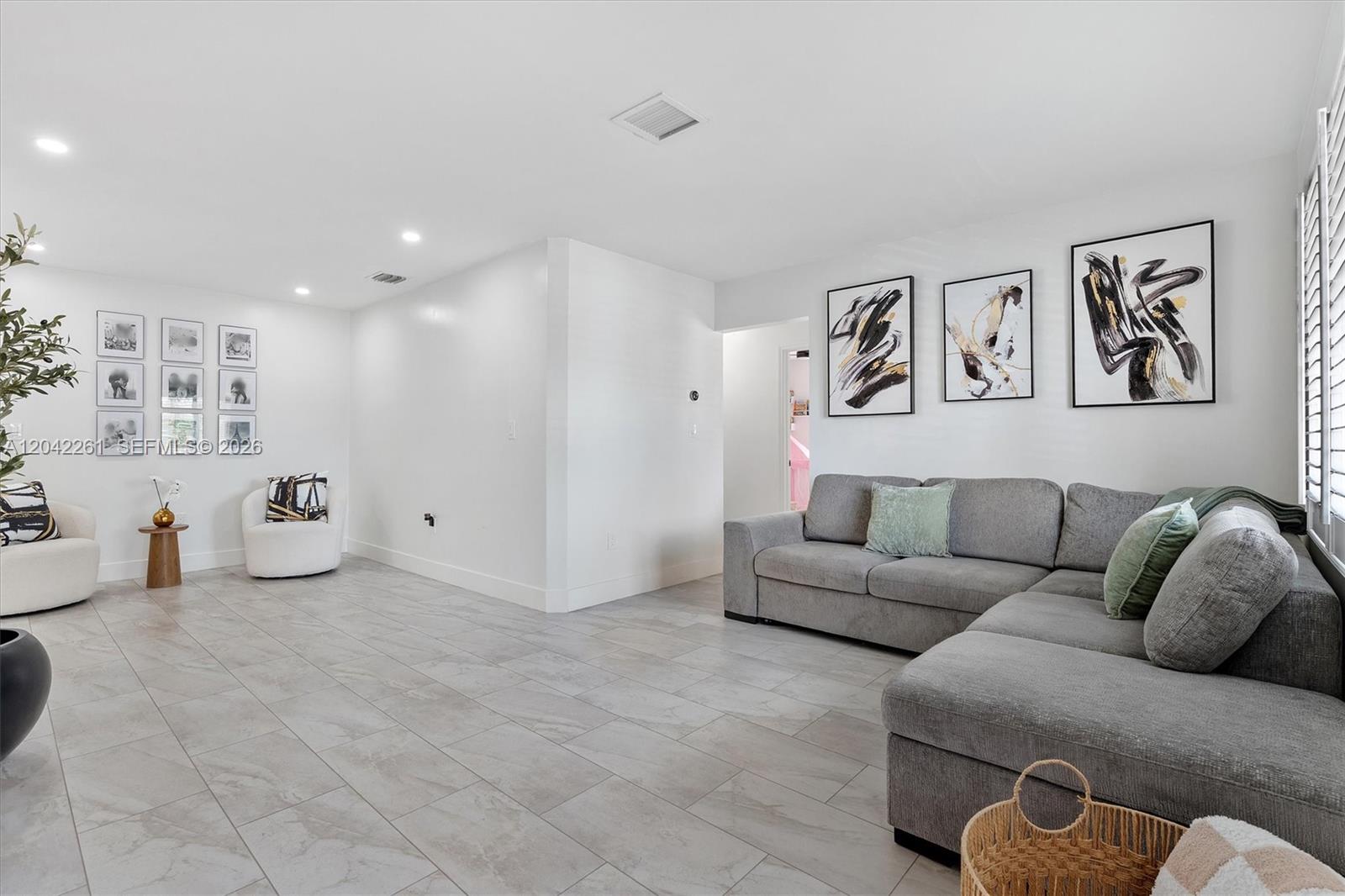 A living room features a grey sectional sofa, white walls, and light-colored tile flooring — 20917 SW 125th Ave Rd, Miami FL 33177, MIAMI, FL