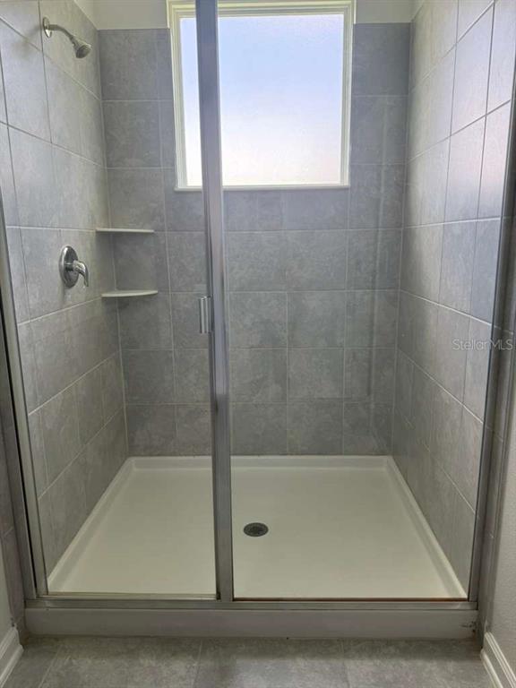 A walk-in shower with gray tiled walls, a glass door, and a white shower pan — 2312 BROOK MARSH LOOP, KISSIMMEE, FL