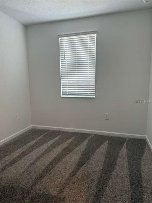 A bedroom with light gray walls, patterned gray carpet, and a window with white blinds — 2312 BROOK MARSH LOOP, KISSIMMEE, FL