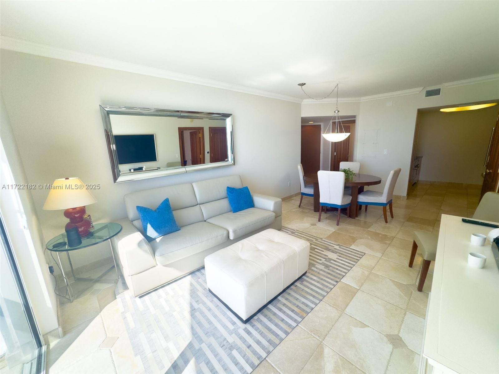 A living and dining area features a white sofa, ottoman, and tiled flooring — 6365 Collins Ave # 1506, Miami Beach FL 33141, MIAMI BEACH, FL