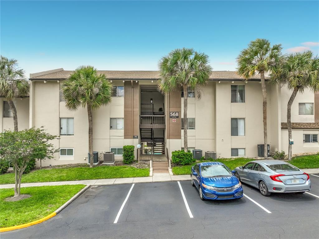 A three-story apartment building exterior with palm trees, parking spaces, and a central stairwell — 568 ORANGE DRIVE UNIT 50, ALTAMONTE SPRINGS, FL