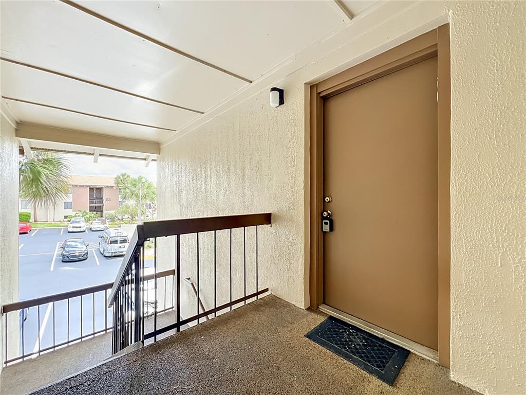 An exterior view of an apartment entrance with a brown door and a metal railing — 568 ORANGE DRIVE UNIT 50, ALTAMONTE SPRINGS, FL