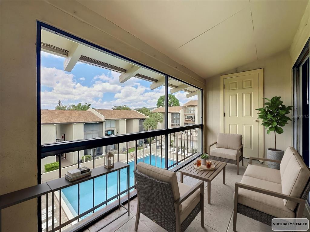 A screened balcony overlooks a swimming pool and apartment buildings with patio furniture arranged inside — 568 ORANGE DRIVE UNIT 50, ALTAMONTE SPRINGS, FL