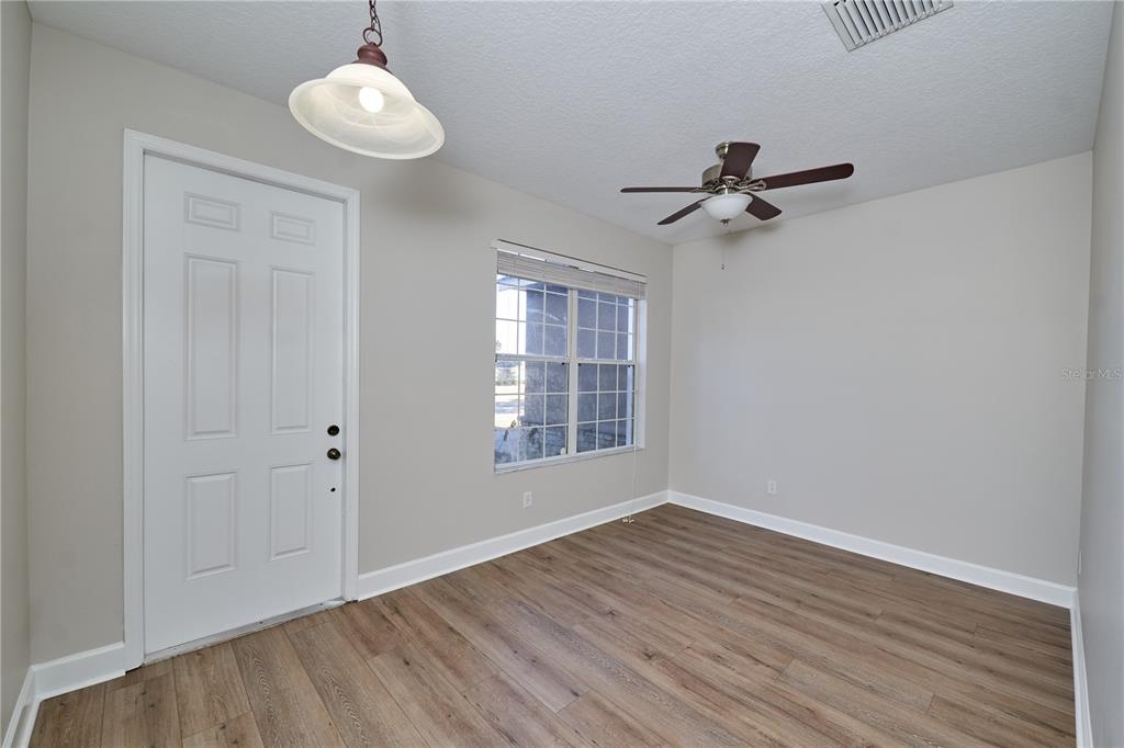 A room with light gray walls, wood-look flooring, a ceiling fan, and a white door — 23903 SARDINIA DRIVE, SORRENTO, FL