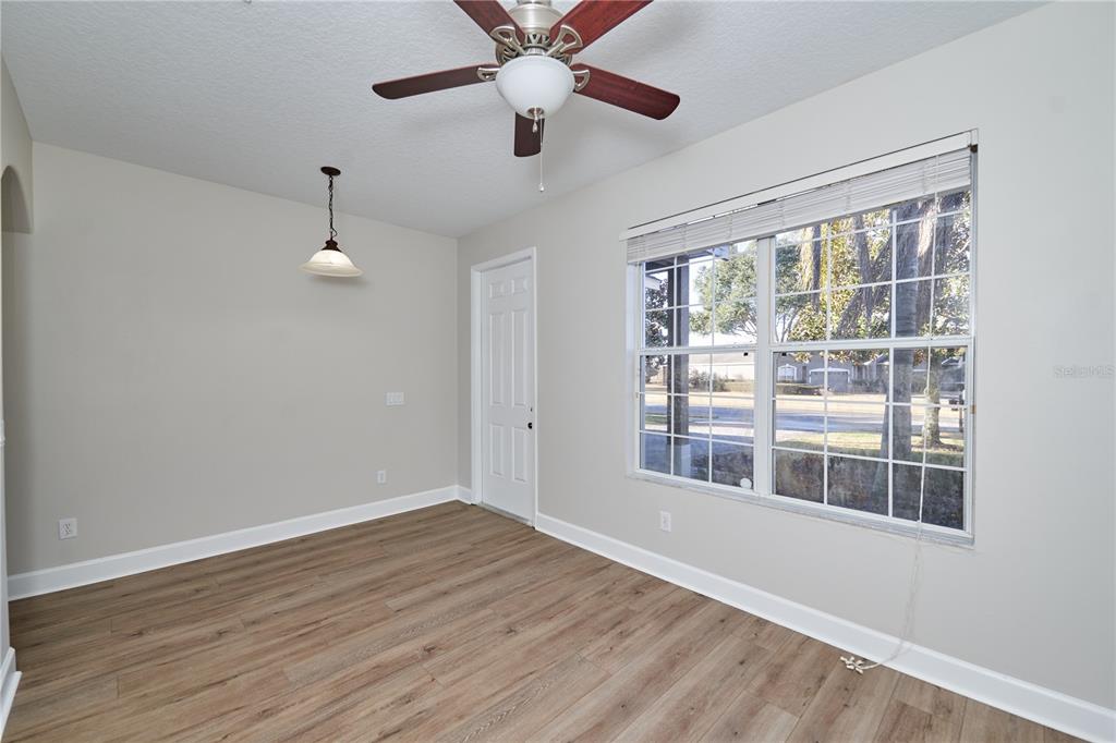 A dining room with light gray walls, wood-look flooring, a ceiling fan, and large windows — 23903 SARDINIA DRIVE, SORRENTO, FL