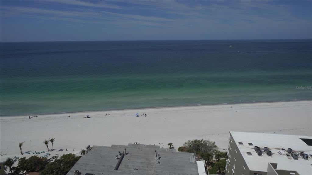 An aerial view shows a multi-story apartment building next to a beach and a road — 19701 GULF BOULEVARD UNIT 212, INDIAN SHORES, FL