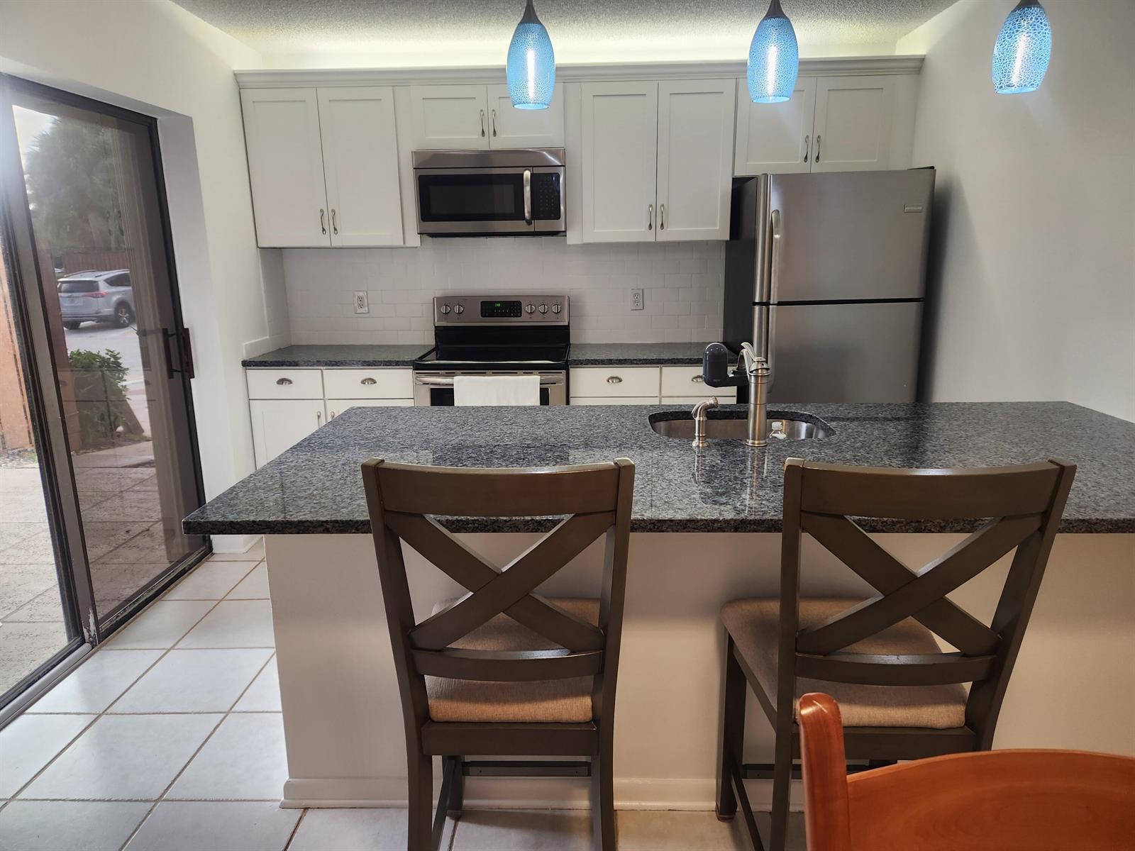 A kitchen features white cabinets, granite countertops, stainless steel appliances, and a breakfast bar — 2813 28th Court, Jupiter FL 33477, JUPITER, FL