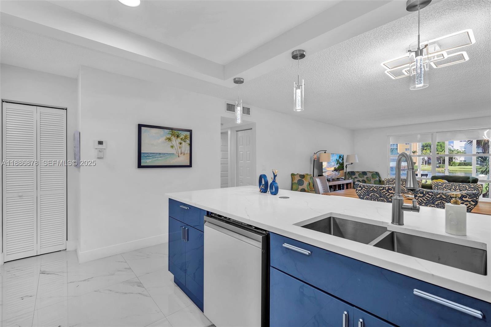 A kitchen island with blue cabinets and a white countertop overlooks a living area — 205 SE 11th Terrace # 101, Dania Beach FL 33004, DANIA BEACH, FL