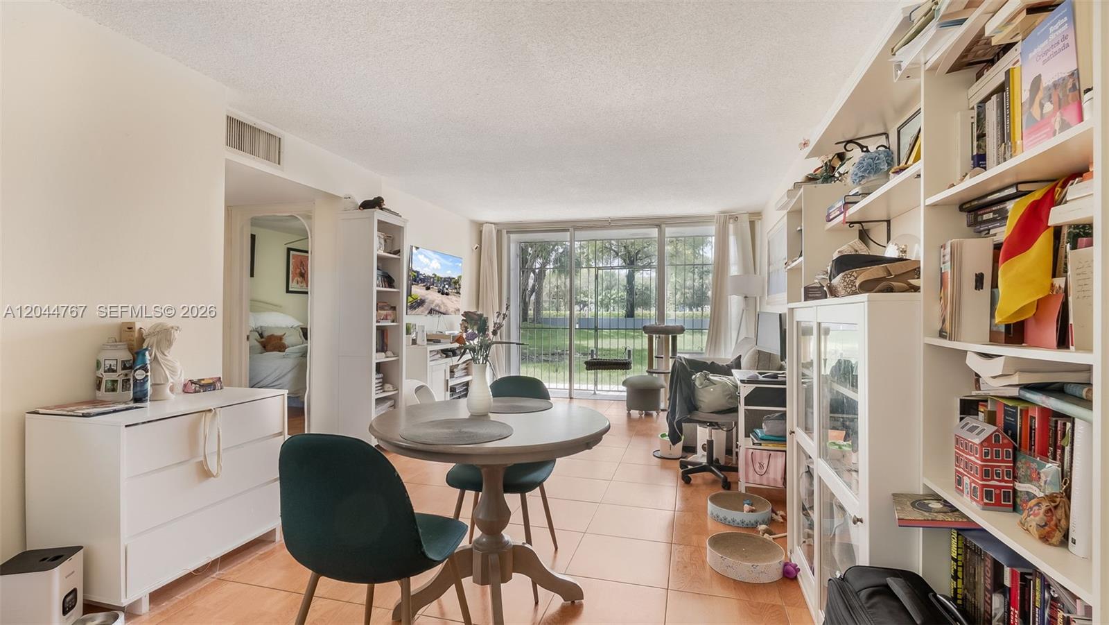 A living and dining area features tile floors, built-in shelving, and a sliding glass door — 110 Fontainebleau Blvd # 101, Miami FL 33172, MIAMI, FL