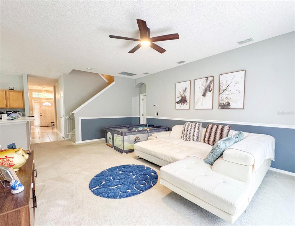 A living room features a white sectional sofa, a playpen, and a blue circular rug — 1207 ROYAL SAINT GEORGE DRIVE, ORLANDO, FL