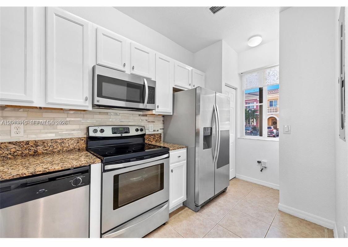 A kitchen features white cabinets, stainless steel appliances, granite countertops, and a tile floor — 1820 SW 89th Ter, Miramar FL 33025, MIRAMAR, FL