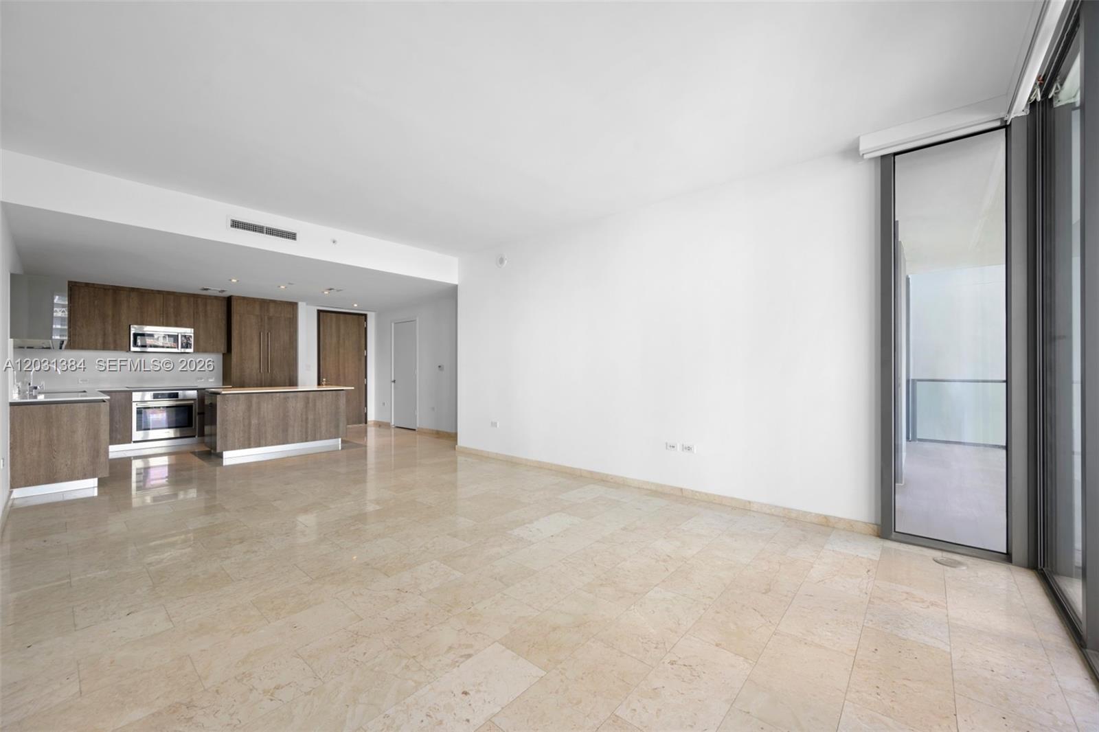 This open-concept living area features light-colored tile flooring, white walls, and an adjacent modern kitchen — 68 SE 6th St # 910, Miami FL 33131, MIAMI, FL