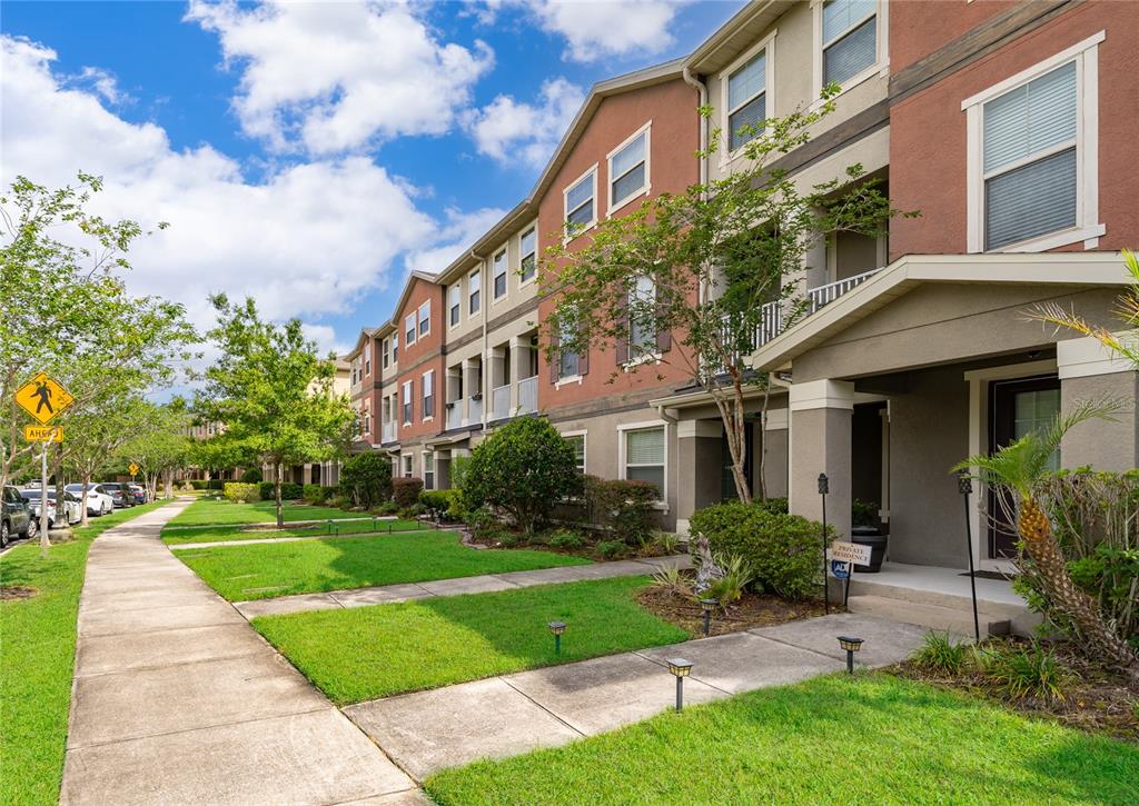 A row of multi-story townhomes with stucco facades, balconies, and a sidewalk along a lawn — 10061 TOWN LAKE DRIVE, ORLANDO, FL