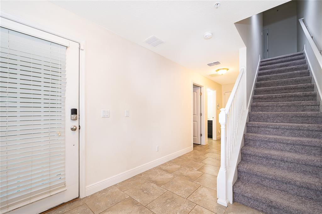 An entryway features tile flooring, a carpeted staircase with a white railing, and a front door — 10061 TOWN LAKE DRIVE, ORLANDO, FL