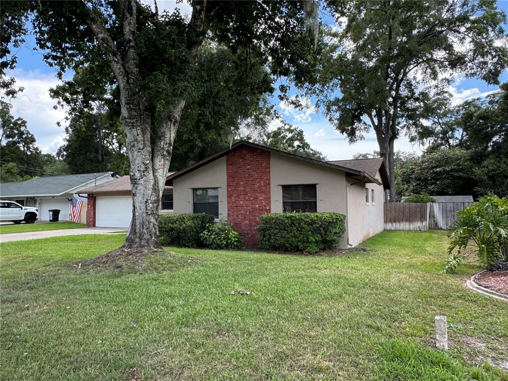 A single-story house with a brick accent wall and a large tree in the yard — 4080 NE 28TH TERRACE, OCALA, FL