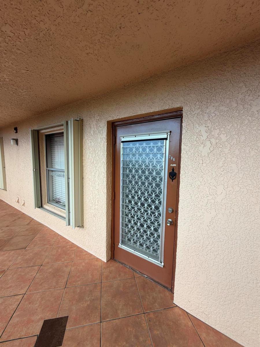 A brown exterior door with a decorative metal screen and a window on a patio — 14575 Bonaire Boulevard # 206, Delray Beach FL 33446, DELRAY BEACH, FL