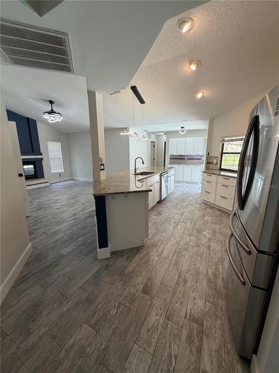 A kitchen with granite countertops and white cabinets opens into a living room with tile floors — 3221 OAKWOOD PLACE, TARPON SPRINGS, FL
