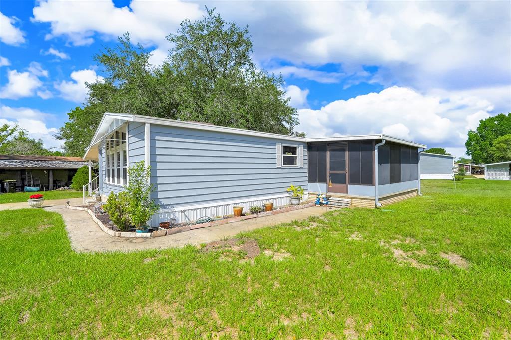 A light blue mobile home with a screened-in porch sits on a grassy lot — 357 WADE PARK COURT, DAVENPORT, FL