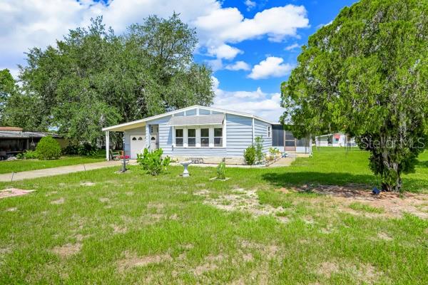 A light blue, single-story house with a covered porch sits on a grassy lot — 357 WADE PARK COURT, DAVENPORT, FL