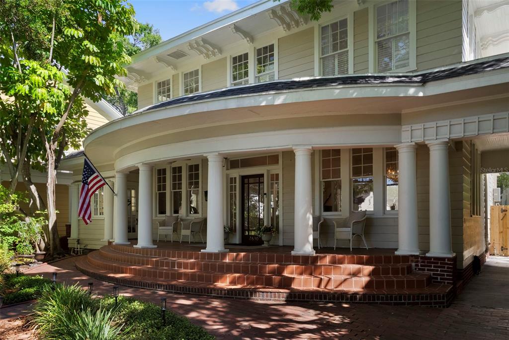 A curved front porch with white columns and brick steps leads to a house entrance — 2630 W PROSPECT ROAD, TAMPA, FL